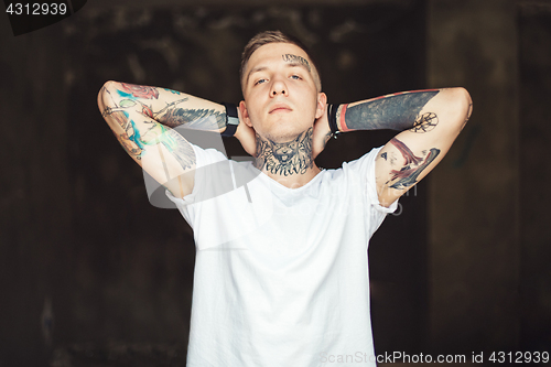 Image of Confident tattooed man posing outside