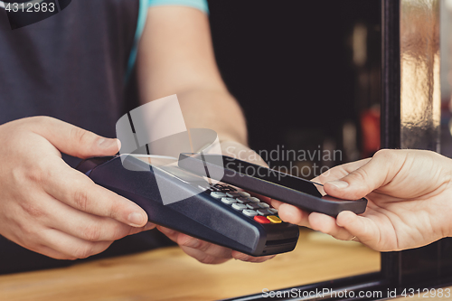 Image of Person paying pay through smartphone using NFC