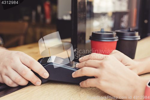 Image of Person using pos terminal at the cafe