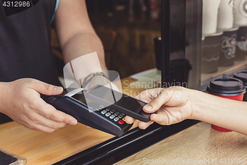 Image of Person paying pay through smartphone using NFC