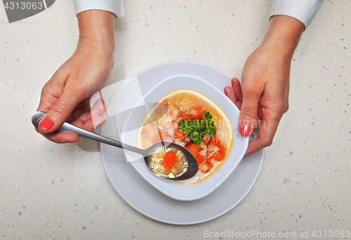 Image of woman holds spoon with soup