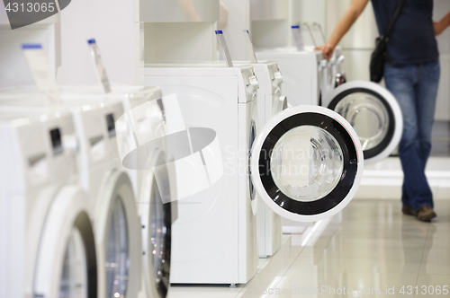 Image of washing machines in appliance store and defocused buyer