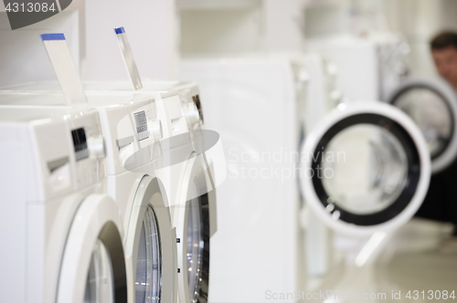 Image of washing machines in appliance store and defocused buyer