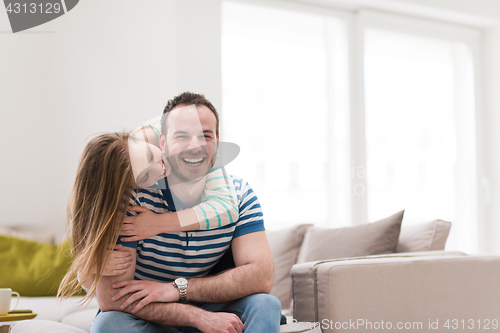 Image of young handsome couple hugging on the sofa