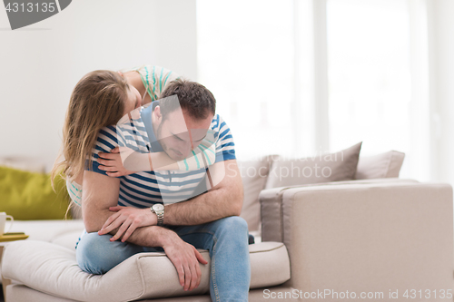 Image of young handsome couple hugging on the sofa