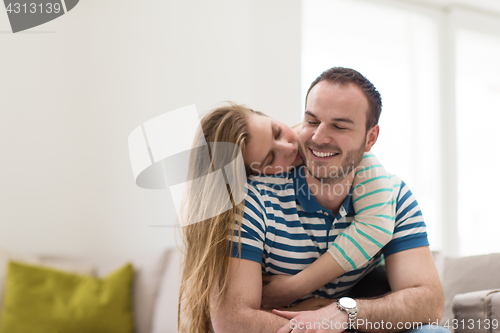 Image of young handsome couple hugging on the sofa