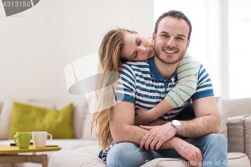 Image of young handsome couple hugging on the sofa