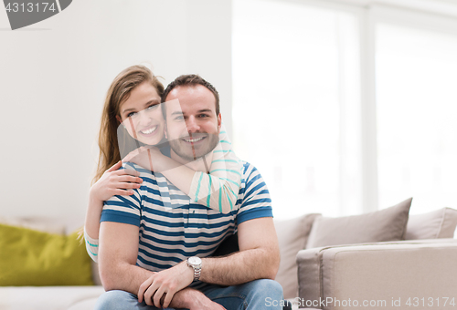 Image of young handsome couple hugging on the sofa