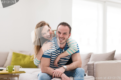 Image of young handsome couple hugging on the sofa