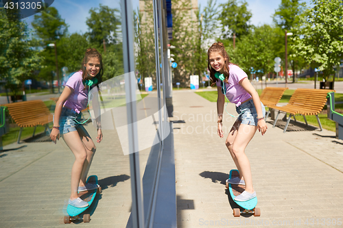 Image of happy teenage girl riding on longboard in summer