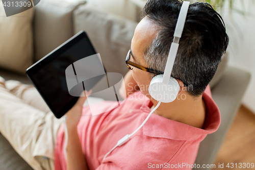 Image of man with tablet pc and headphones at home