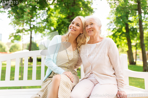 Image of daughter with senior mother hugging on park bench