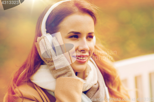 Image of happy woman with headphones in autumn park