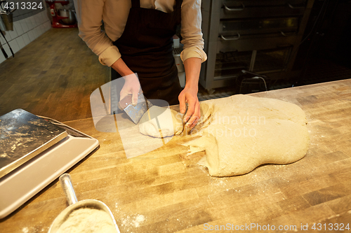 Image of baker portioning dough with bench cutter at bakery