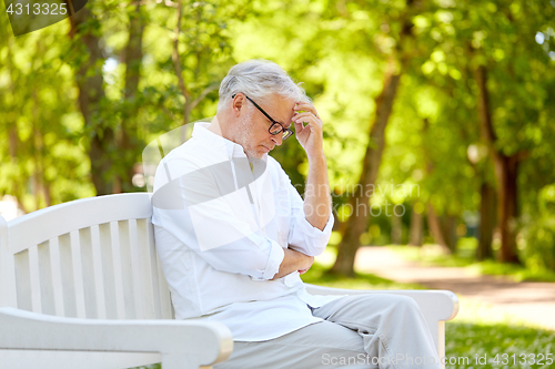 Image of thoughtful senior man sitting at summer park