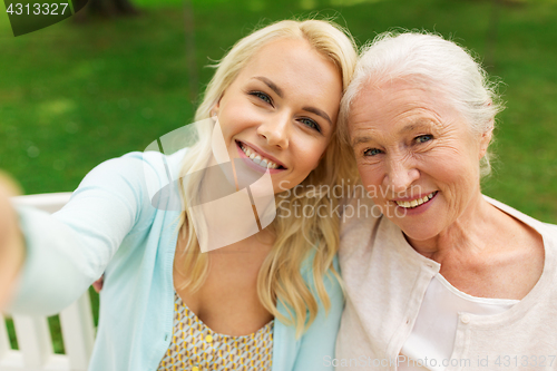 Image of daughter and senior mother taking selfie at park