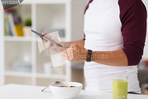 Image of man with tablet pc having breakfast at home