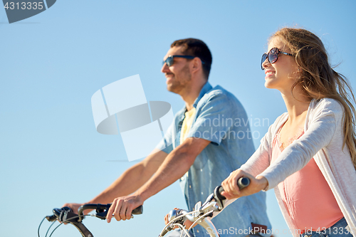 Image of happy young couple riding bicycles in summer