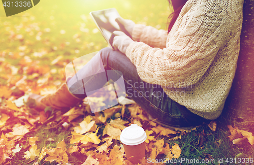 Image of woman with tablet pc and coffee in autumn park