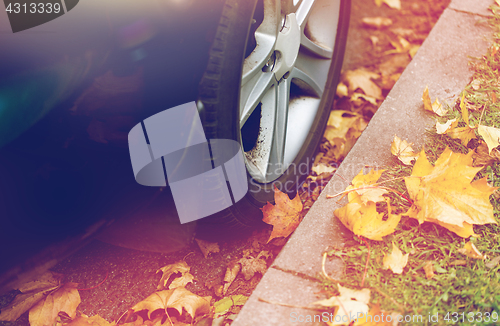 Image of close up of car wheel and autumn leaves