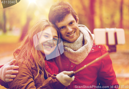 Image of couple taking selfie by smartphone in autumn park