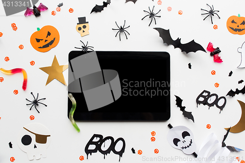 Image of tablet pc, halloween party decorations and candies