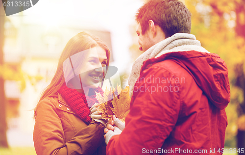 Image of happy couple with maple leaves in autumn park