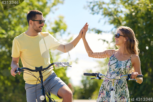 Image of happy couple with bicycles making high five
