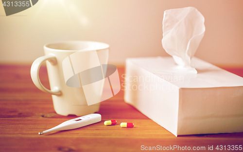 Image of cup of tea, paper wipes and thermometer with pills