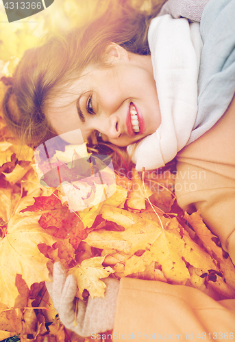 Image of beautiful happy woman lying on autumn leaves