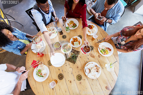 Image of happy friends eating at restaurant