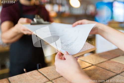 Image of bartender showing menu to customer at bar