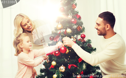 Image of happy family decorating christmas tree at home