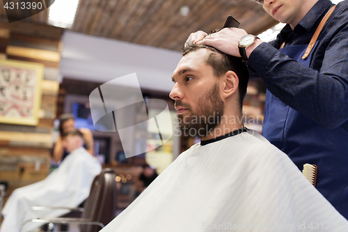 Image of man and barber cutting hair at barbershop