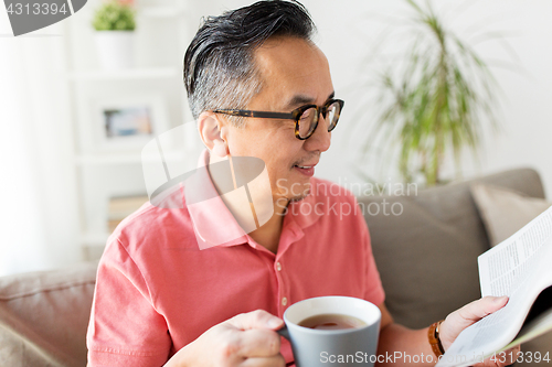 Image of man drinking coffee and reading newspaper at home