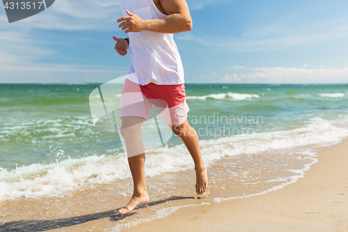 Image of happy man running along summer beach