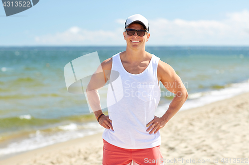 Image of smiling young man in sunglasses on summer beach
