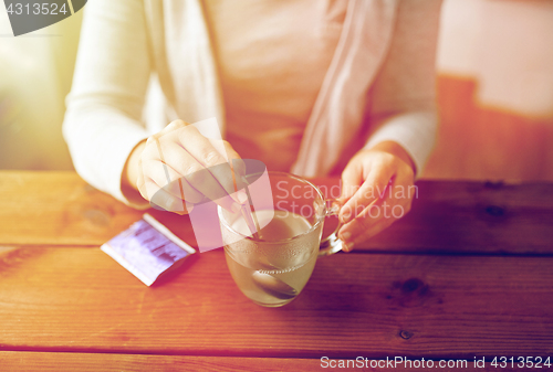 Image of woman stirring medication in cup with spoon