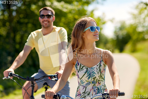 Image of happy young couple riding bicycles in summer