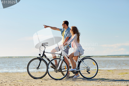 Image of happy young couple riding bicycles at seaside