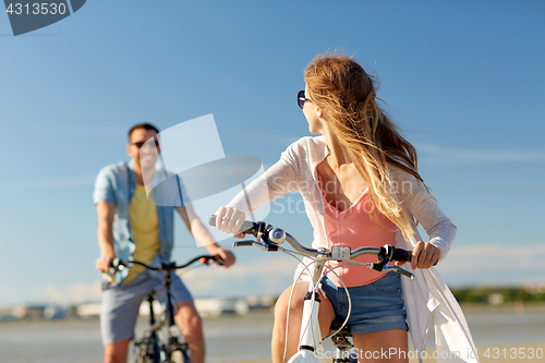 Image of happy young couple riding bicycles at seaside