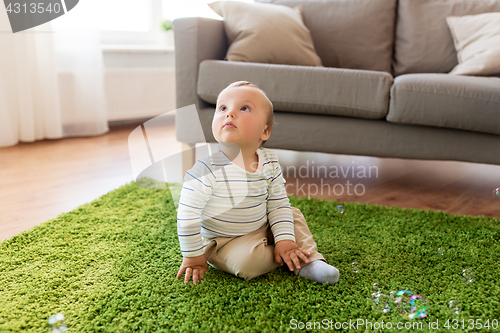 Image of baby boy playing with soap bubbles at home