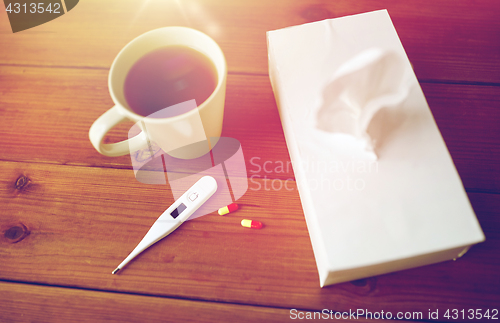 Image of cup of tea, paper wipes and thermometer with pills