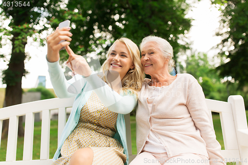 Image of daughter and senior mother taking selfie at park