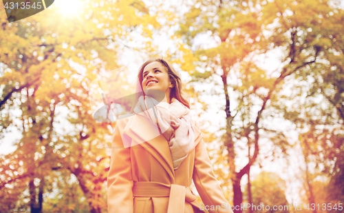 Image of beautiful happy young woman walking in autumn park