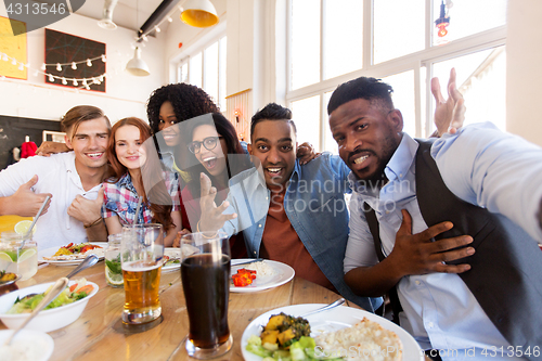 Image of happy friends taking selfie at restaurant or bar