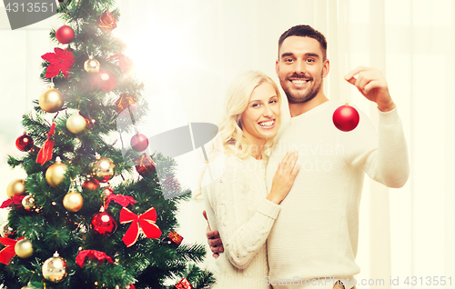 Image of happy couple decorating christmas tree at home