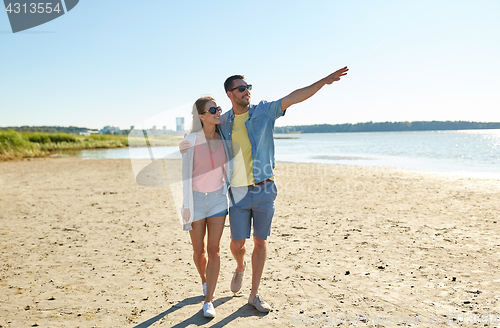 Image of happy couple walking along summer beach