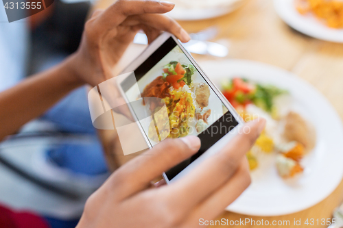 Image of hands with smartphone picturing food at restaurant