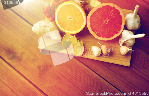 Image of citrus fruits, ginger and garlic on wood